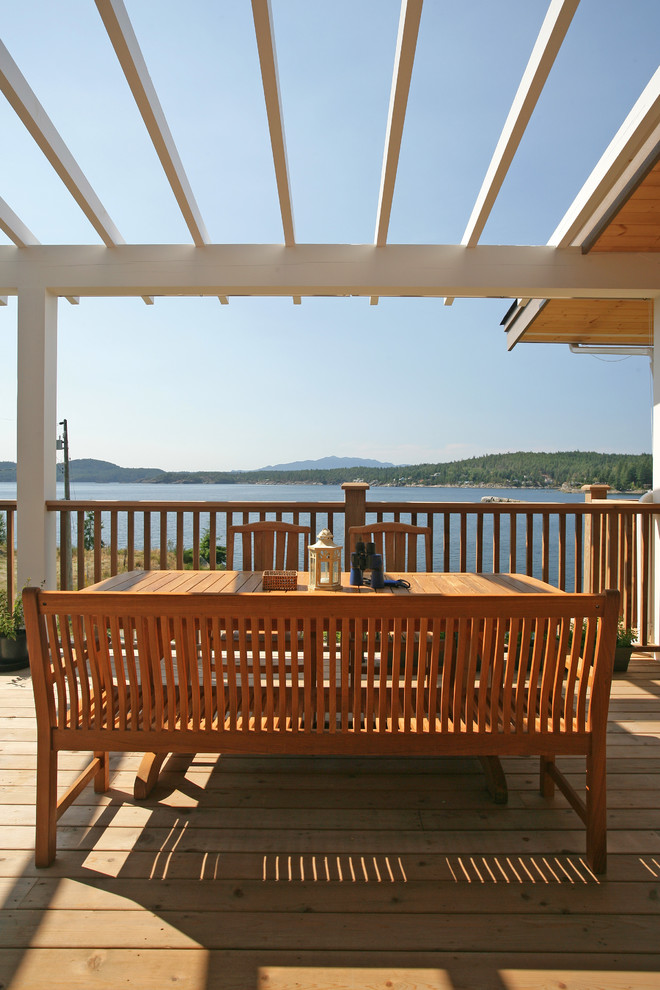 This is an example of a beach style deck in Vancouver with a pergola.