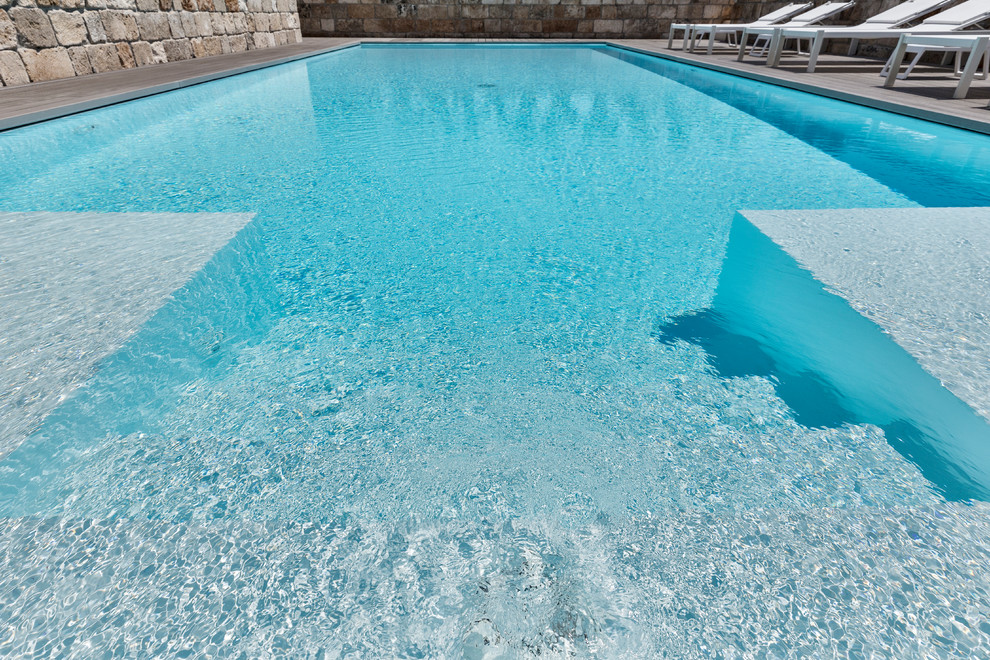 На фото: прямоугольный бассейн-инфинити среднего размера на заднем дворе в стиле модернизм с настилом с