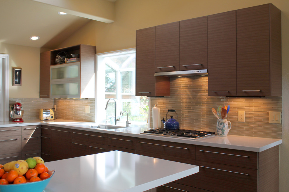 Photo of a contemporary u-shaped eat-in kitchen in San Francisco with an undermount sink, flat-panel cabinets, medium wood cabinets, marble benchtops, beige splashback, glass tile splashback and stainless steel appliances.