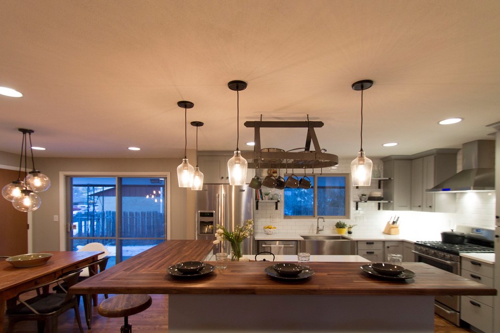 Inspiration for a mid-sized transitional l-shaped medium tone wood floor eat-in kitchen remodel in Denver with a farmhouse sink, shaker cabinets, gray cabinets, quartz countertops, white backsplash, ceramic backsplash, stainless steel appliances and an island