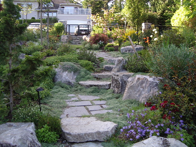 This is an example of a large traditional courtyard garden in Vancouver with a garden path and concrete pavers.