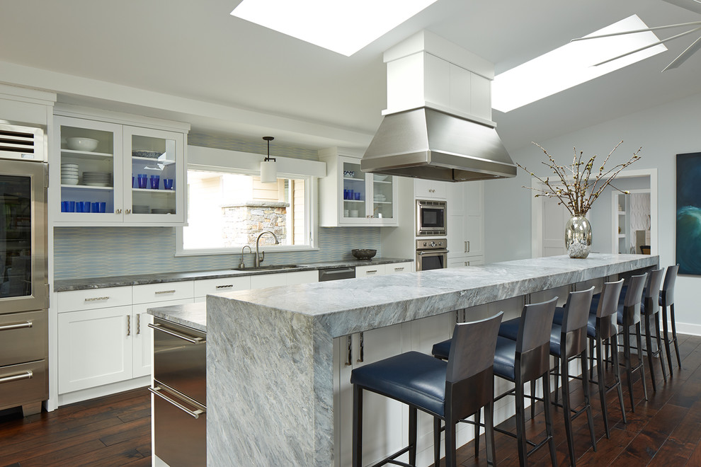 This is an example of a large transitional kitchen in Minneapolis with an undermount sink, white cabinets, quartzite benchtops, ceramic splashback, stainless steel appliances, dark hardwood floors, with island, glass-front cabinets and multi-coloured splashback.