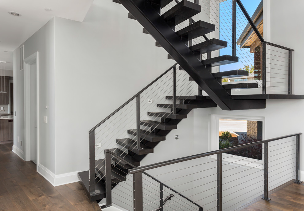 This is an example of an expansive contemporary metal floating staircase in Portland with metal risers and cable railing.