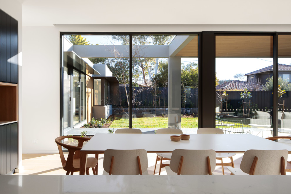 This is an example of a contemporary dining room in Canberra - Queanbeyan with white walls and light hardwood floors.
