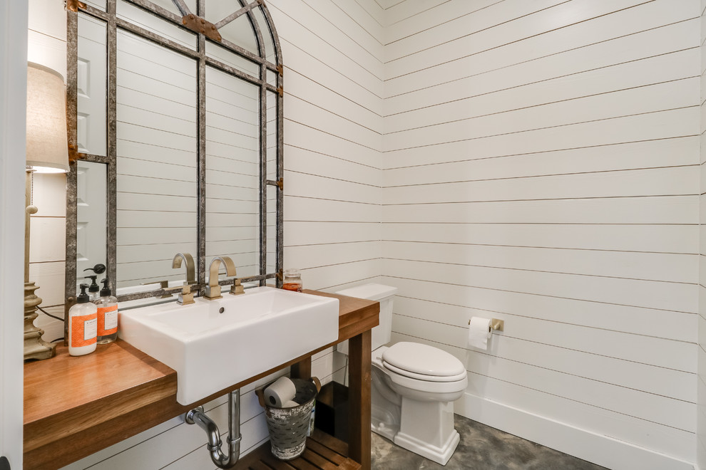 Country powder room in Jackson with open cabinets, medium wood cabinets, a two-piece toilet, white walls, a vessel sink, wood benchtops, brown floor and brown benchtops.