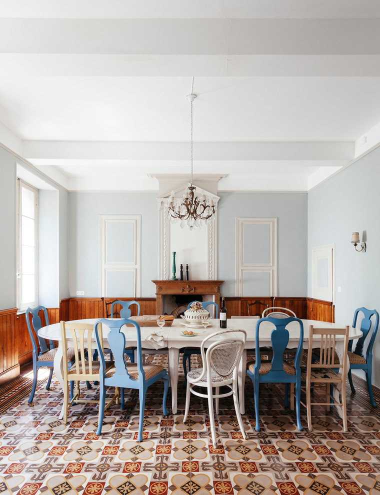 This is an example of a large mediterranean separate dining room in Toulouse with grey walls, a standard fireplace and a wood fireplace surround.