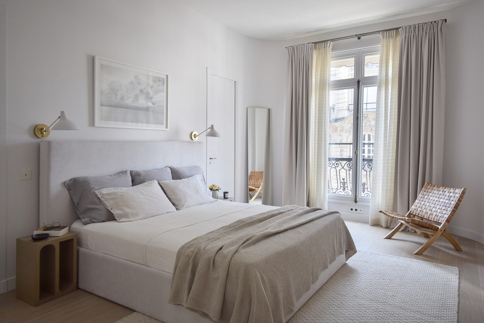 Photo of a large contemporary master bedroom in Paris with white walls and light hardwood floors.