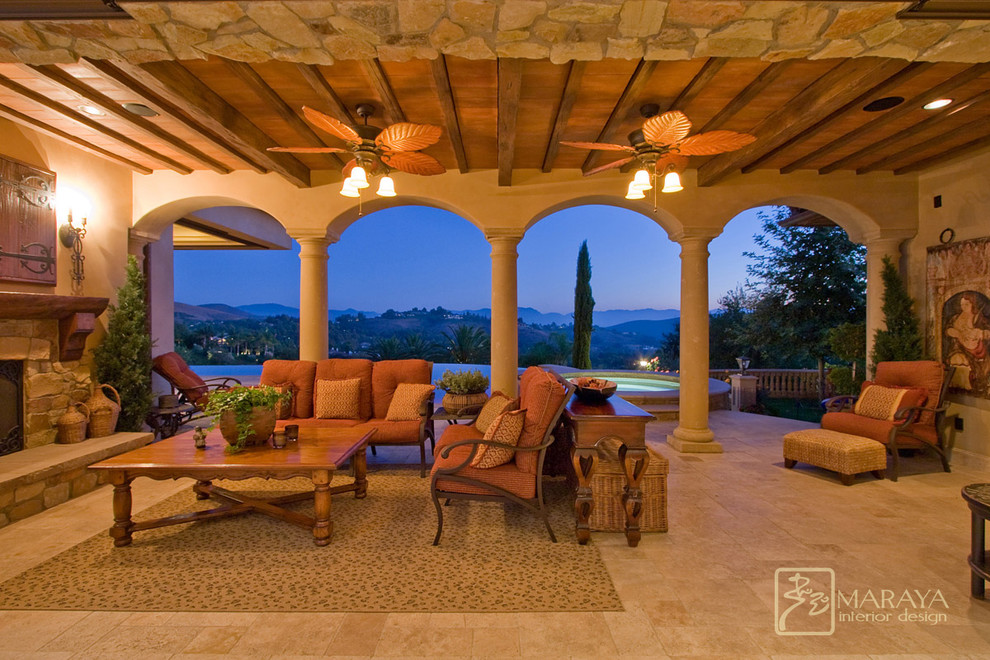 Large mediterranean backyard patio in Los Angeles with a fire feature, tile and a roof extension.