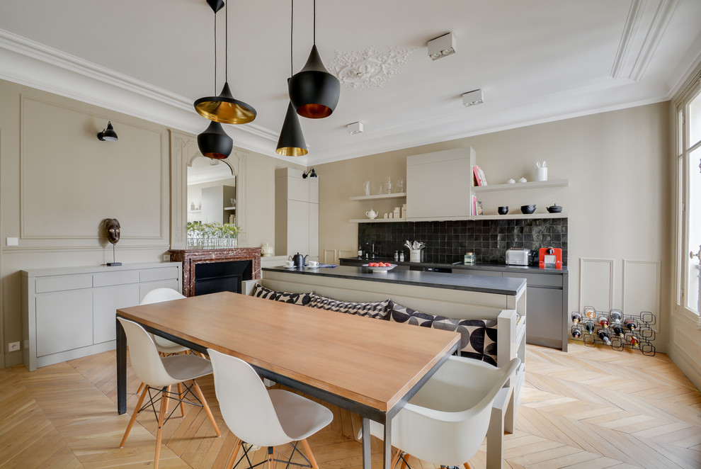 This is an example of a contemporary galley eat-in kitchen in Paris with black splashback, light hardwood floors, with island, flat-panel cabinets, black cabinets, granite benchtops and stone tile splashback.