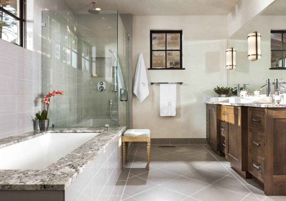 Inspiration for a country master bathroom in Other with a vessel sink, recessed-panel cabinets, dark wood cabinets, marble benchtops, an undermount tub, a curbless shower, gray tile, white walls and porcelain floors.