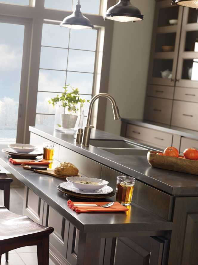 Example of a large transitional galley slate floor enclosed kitchen design with an undermount sink, shaker cabinets, brown cabinets, quartz countertops, beige backsplash, mosaic tile backsplash, stainless steel appliances and an island