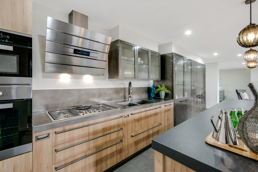 Inspiration for an industrial galley eat-in kitchen in Melbourne with an integrated sink, raised-panel cabinets, medium wood cabinets, stainless steel benchtops, metallic splashback, stainless steel appliances, multiple islands and ceramic floors.