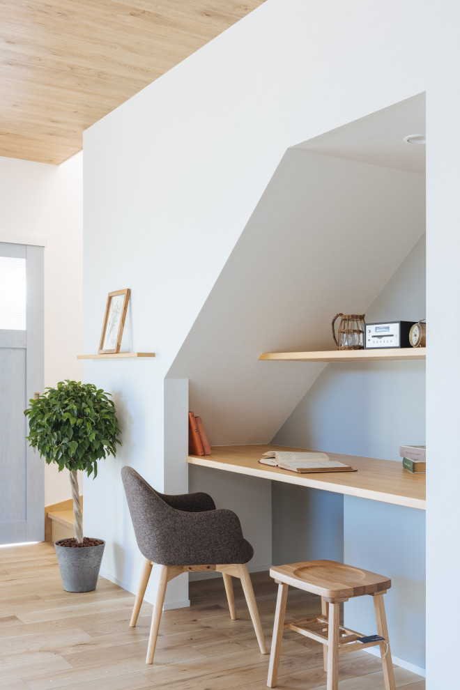 Skandinavisk inredning av ett litet hemmabibliotek, med grå väggar, ljust trägolv, ett inbyggt skrivbord och beiget golv