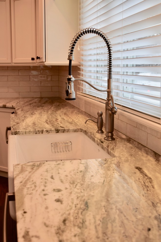 Inspiration for a large transitional u-shaped dark wood floor and brown floor enclosed kitchen remodel with a farmhouse sink, beaded inset cabinets, white cabinets, granite countertops, beige backsplash, ceramic backsplash, stainless steel appliances, an island and multicolored countertops