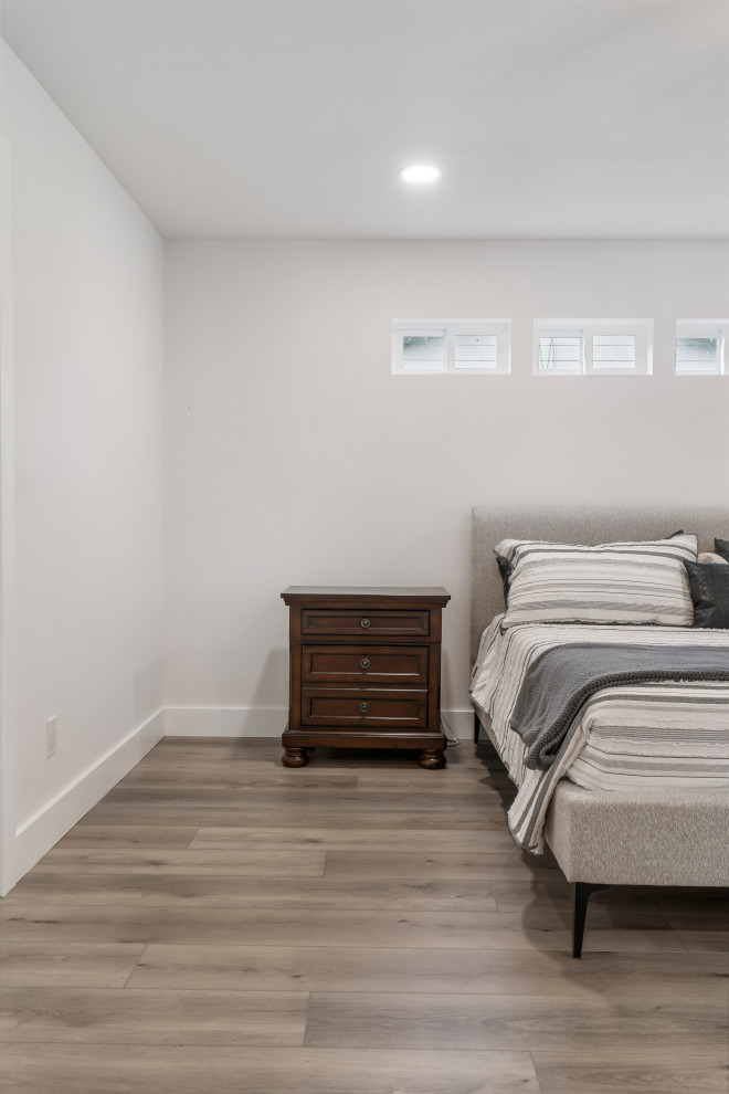 Diseño de dormitorio principal minimalista de tamaño medio con paredes blancas, suelo vinílico y suelo marrón