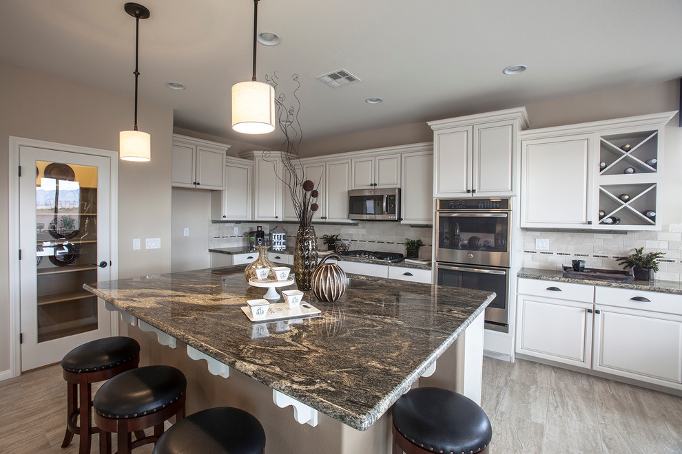 Photo of a large traditional u-shaped eat-in kitchen in Las Vegas with a double-bowl sink, beaded inset cabinets, light wood cabinets, granite benchtops, beige splashback, stone tile splashback, stainless steel appliances, medium hardwood floors and with island.