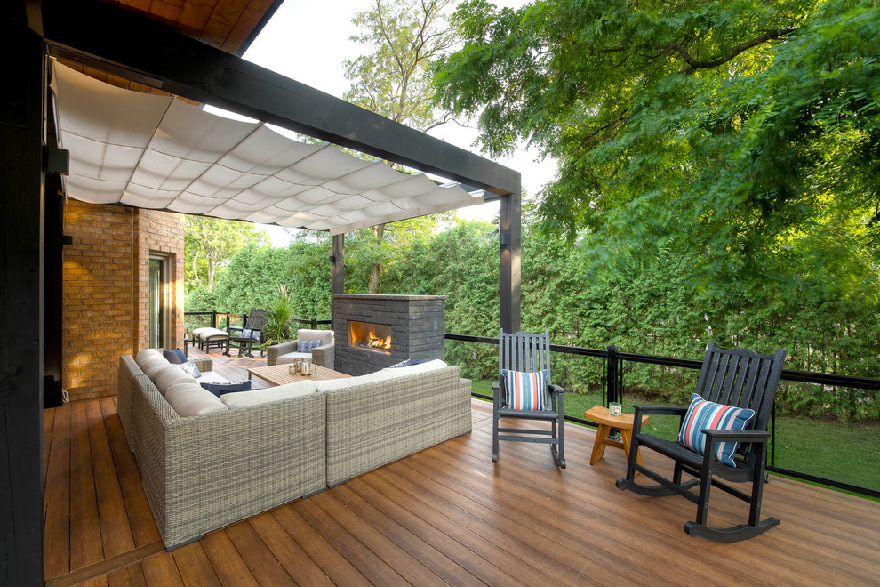 Design ideas for a modern backyard deck in Toronto with with fireplace and a pergola.