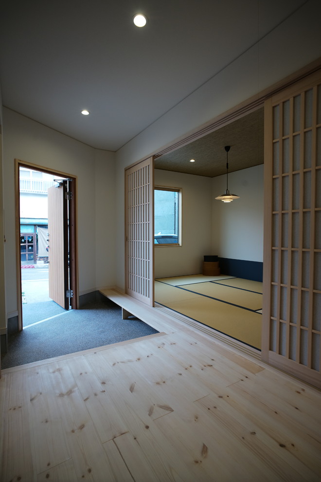Inspiration for an asian entryway in Other with white walls, medium hardwood floors, a single front door, a dark wood front door and beige floor.