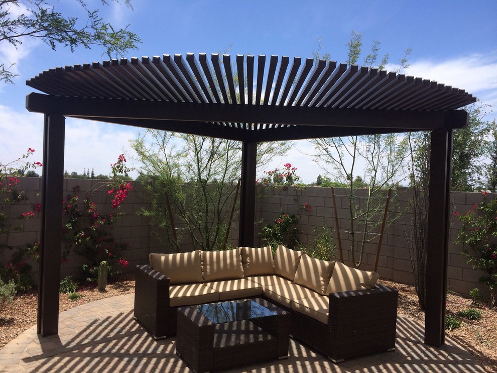 Inspiration for a small backyard patio in Phoenix with natural stone pavers and a pergola.