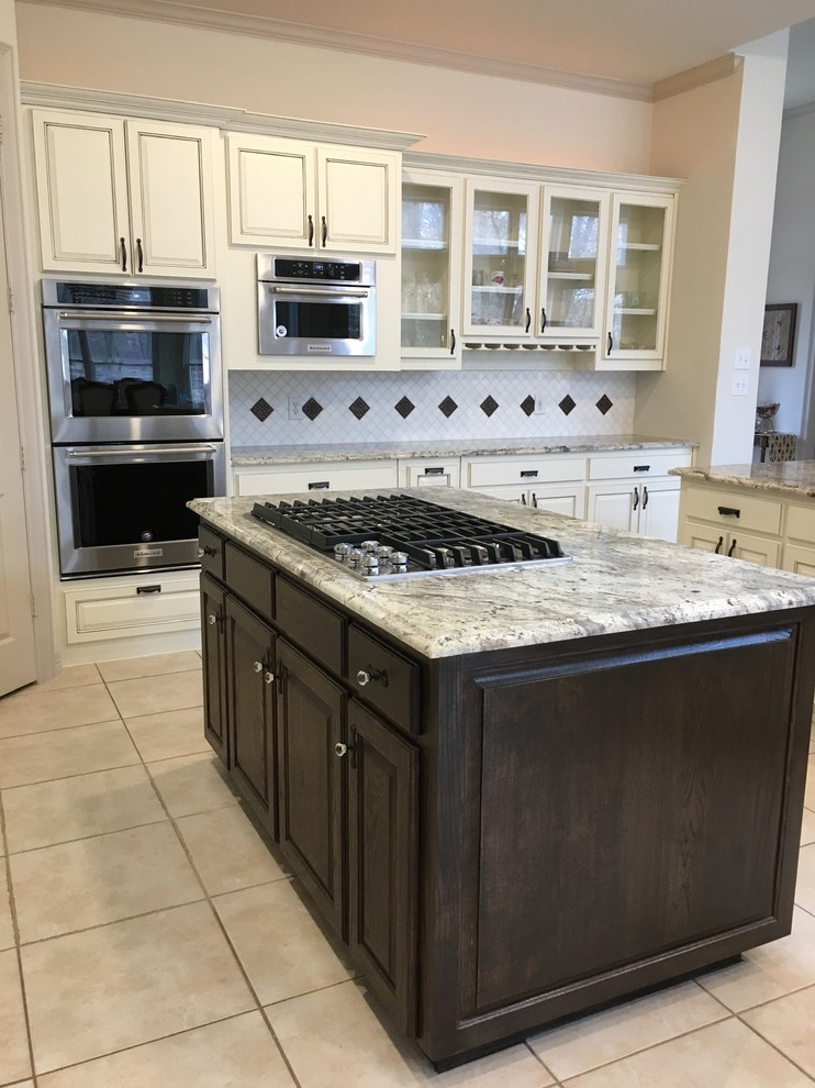 Inspiration for a mid-sized traditional u-shaped eat-in kitchen in Dallas with a farmhouse sink, raised-panel cabinets, white cabinets, granite benchtops, white splashback, mosaic tile splashback, stainless steel appliances, ceramic floors, multiple islands, white floor and white benchtop.