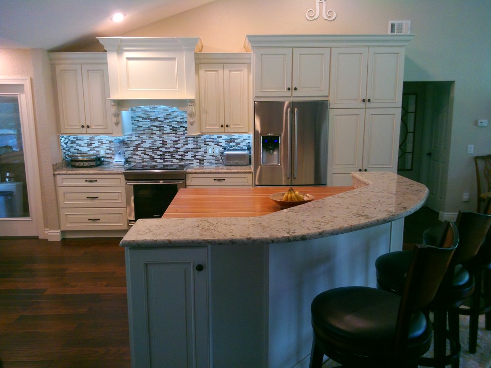 Large traditional u-shaped eat-in kitchen in Tampa with a drop-in sink, flat-panel cabinets, white cabinets, granite benchtops, beige splashback, ceramic splashback, stainless steel appliances, light hardwood floors and with island.