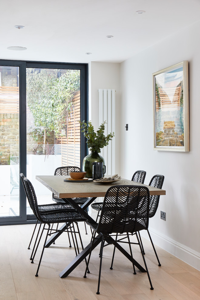 Photo of a transitional dining room in London with light hardwood floors, no fireplace, beige floor and grey walls.