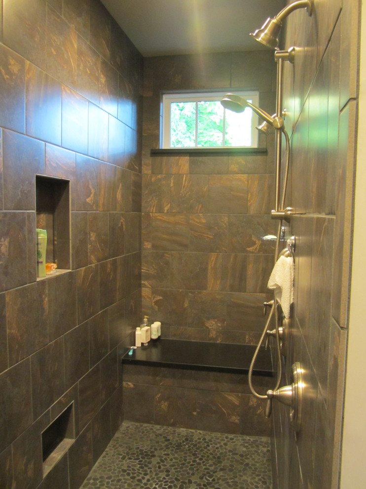 This is an example of an arts and crafts bathroom in Denver with a double shower, brown tile, porcelain tile, brown walls and pebble tile floors.