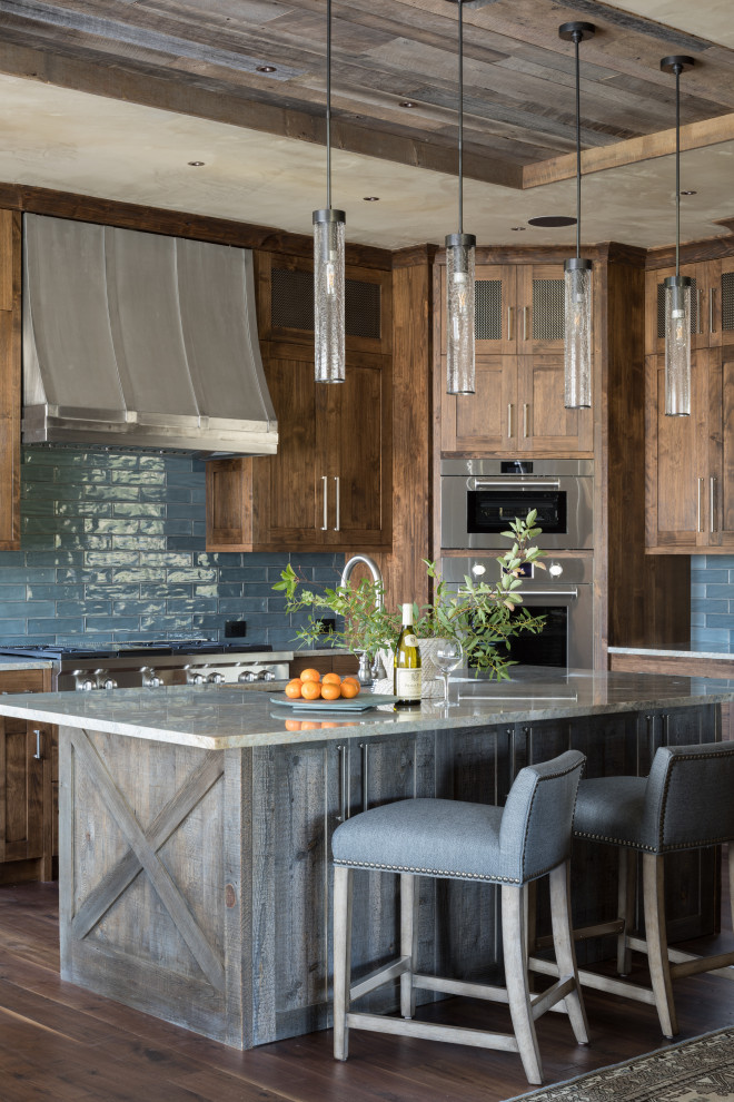 This is an example of a country l-shaped kitchen in Jackson with shaker cabinets, dark wood cabinets, blue splashback, stainless steel appliances, dark hardwood floors, with island and brown floor.