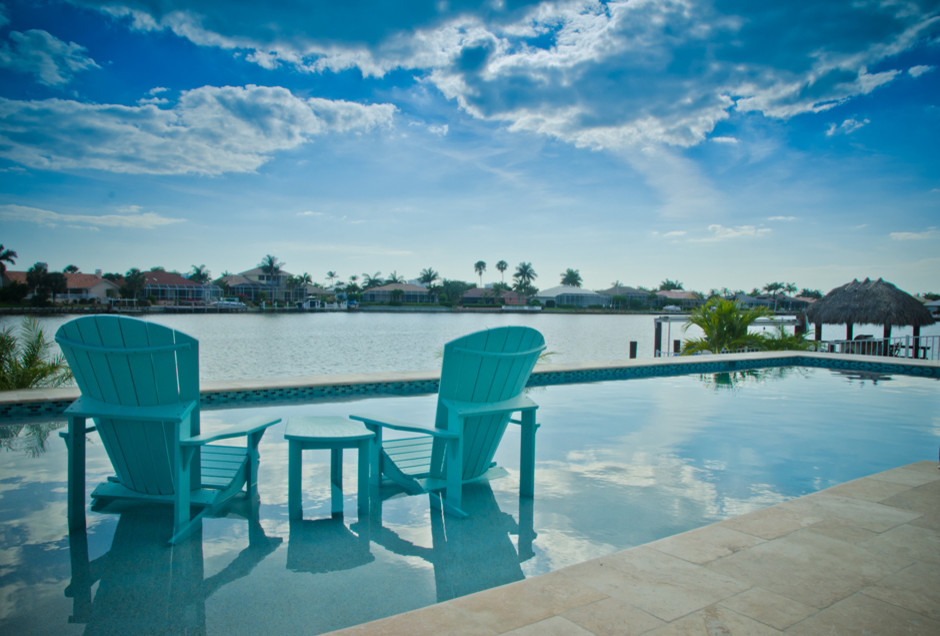 Expansive beach style backyard custom-shaped pool in Miami with natural stone pavers.