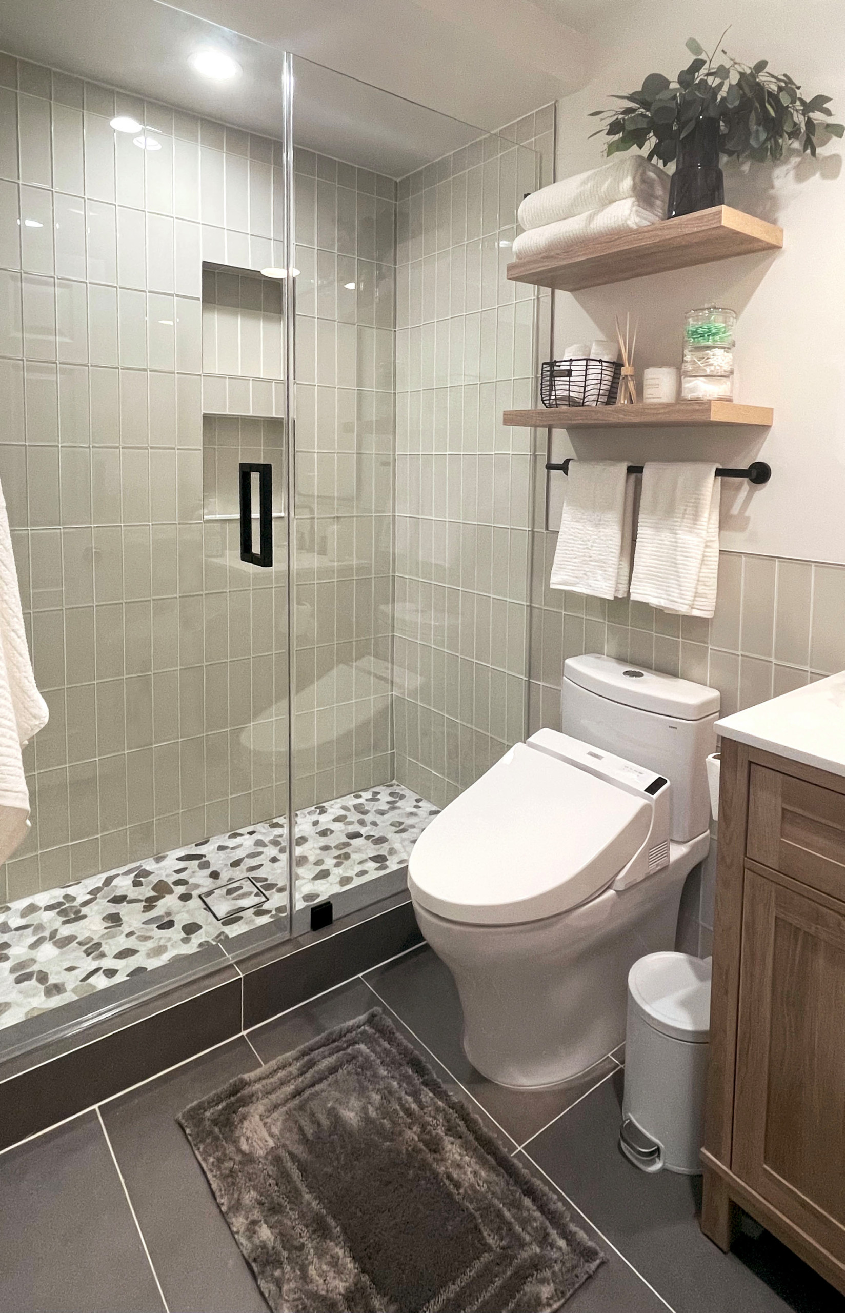 Light, glass tiles on the walls and a walk-in shower gives this small bathroom a