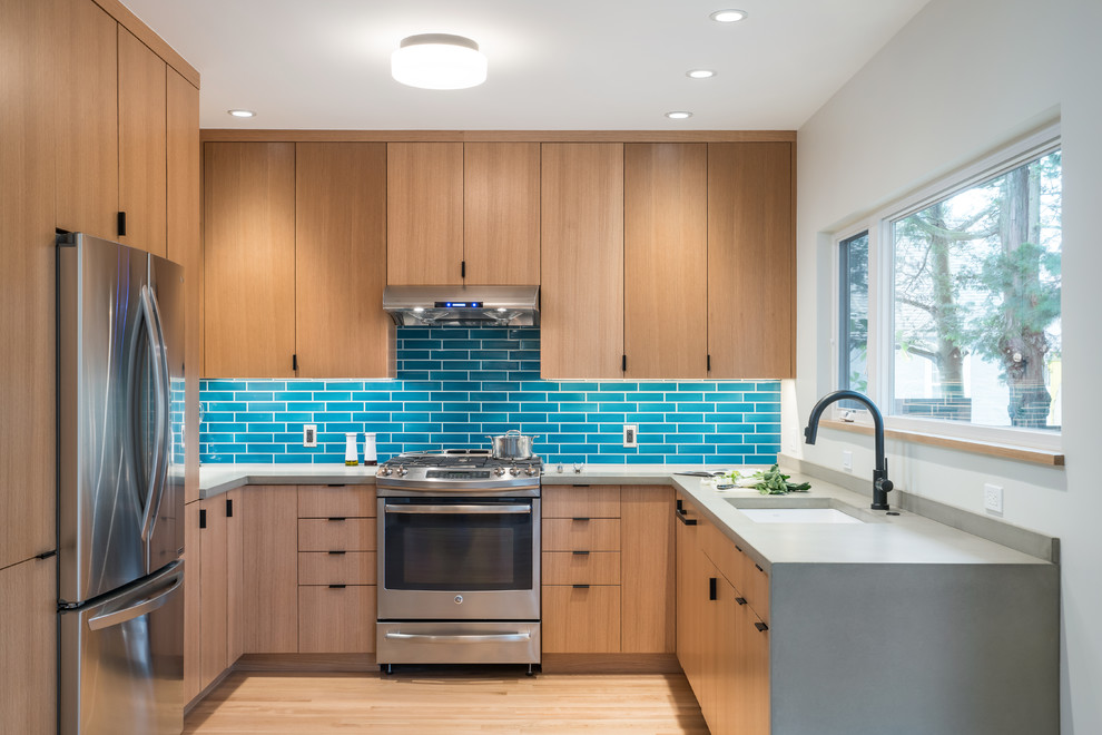 Photo of a mid-sized contemporary u-shaped eat-in kitchen in Portland with an undermount sink, flat-panel cabinets, blue splashback, subway tile splashback, stainless steel appliances, light hardwood floors, no island, beige floor, grey benchtop, medium wood cabinets and quartz benchtops.
