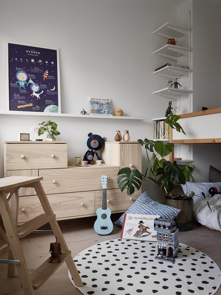 Inspiration for a mid-sized scandinavian kids' playroom for kids 4-10 years old and boys in Stockholm with white walls and light hardwood floors.