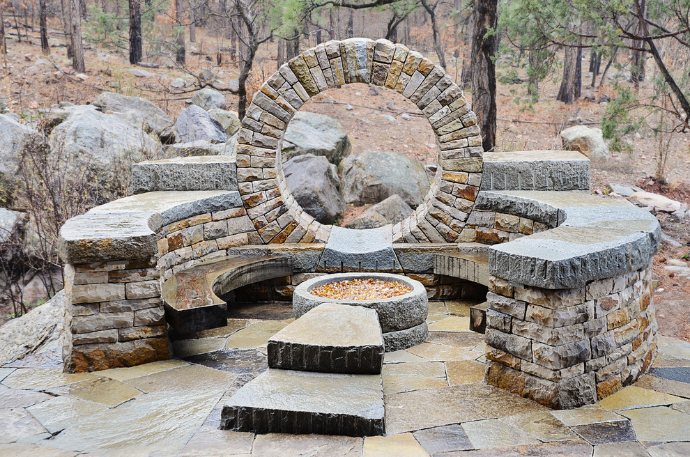 This is an example of an arts and crafts backyard patio in Denver with a fire feature, natural stone pavers and no cover.