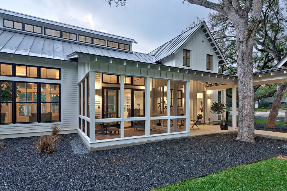 This is an example of a mid-sized country two-storey white house exterior in Austin with concrete fiberboard siding, a gable roof, a metal roof and board and batten siding.