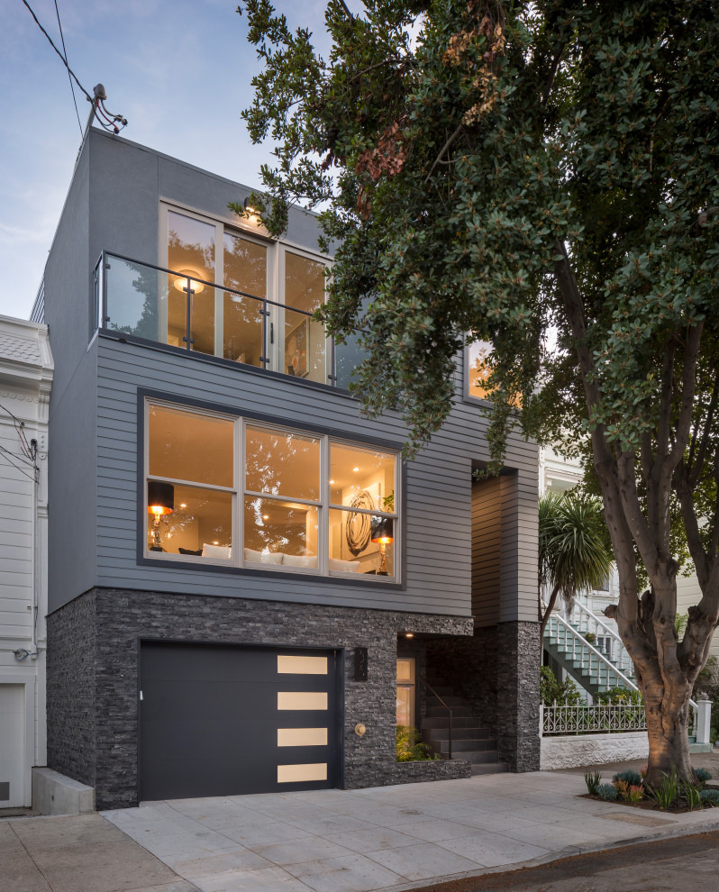 This is an example of a contemporary three-storey grey house exterior in San Francisco with wood siding, a flat roof and clapboard siding.