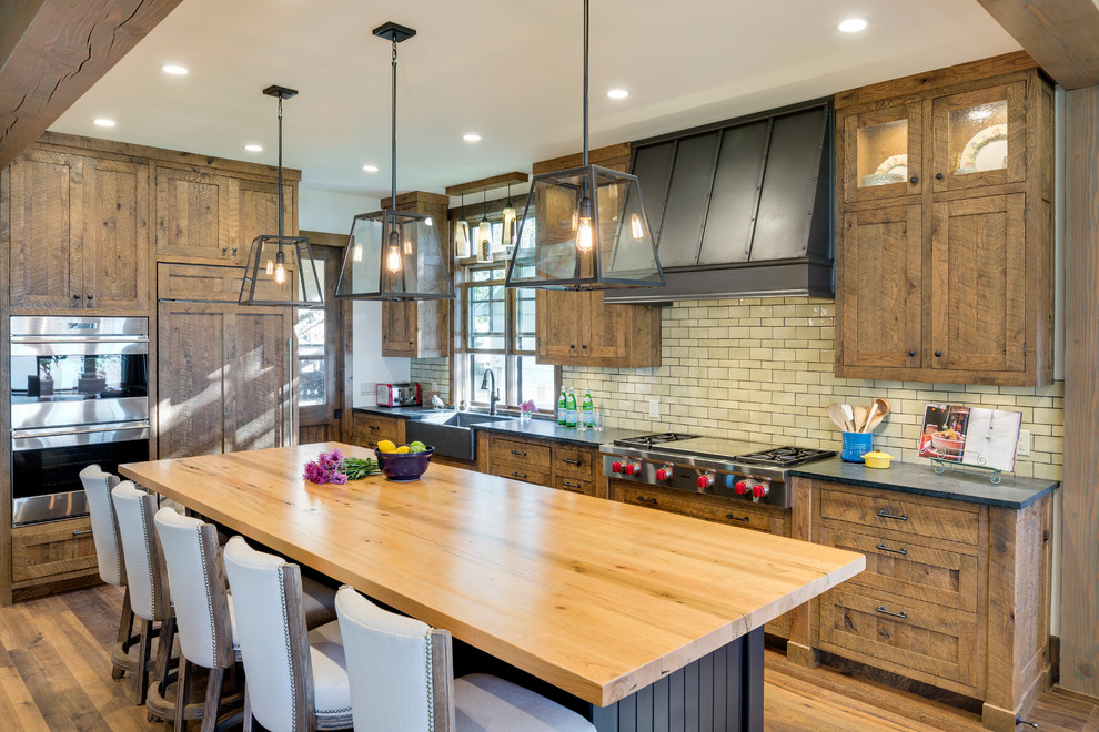 Photo of a mid-sized country l-shaped kitchen in Minneapolis with a farmhouse sink, shaker cabinets, subway tile splashback, panelled appliances, medium hardwood floors, with island, medium wood cabinets and white splashback.