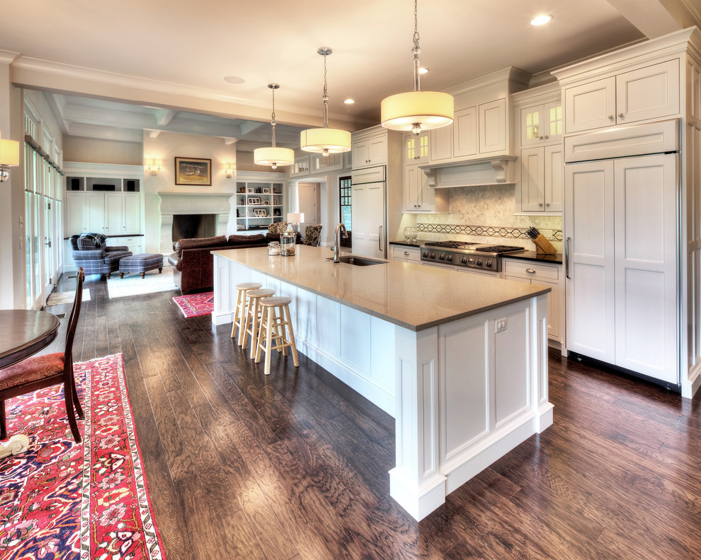 Example of a mid-sized beach style single-wall medium tone wood floor open concept kitchen design with a single-bowl sink, flat-panel cabinets, white cabinets, quartzite countertops, beige backsplash, ceramic backsplash, stainless steel appliances and an island