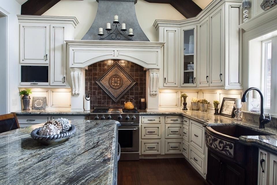 Eat-in kitchen - large transitional l-shaped dark wood floor and brown floor eat-in kitchen idea in Birmingham with a farmhouse sink, raised-panel cabinets, white cabinets, brown backsplash, stainless steel appliances and an island