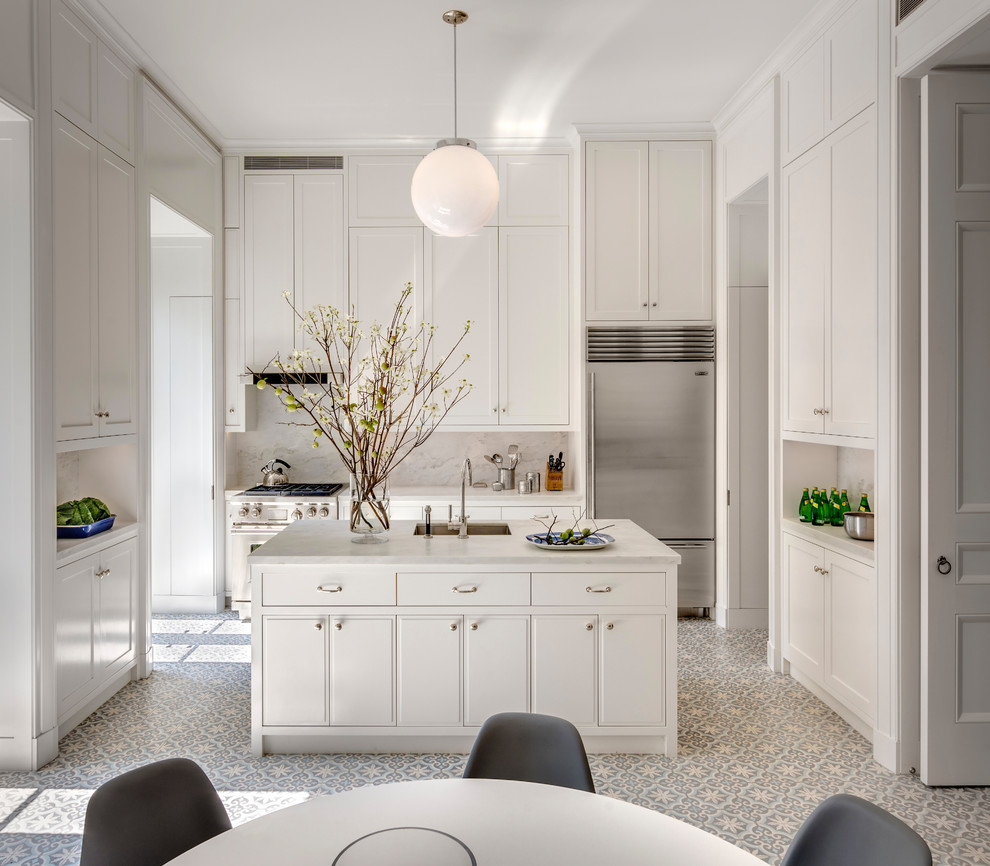 This is an example of a mid-sized contemporary u-shaped eat-in kitchen in New York with an undermount sink, recessed-panel cabinets, white cabinets, marble benchtops, white splashback, marble splashback, stainless steel appliances, cement tiles, with island, multi-coloured floor and white benchtop.