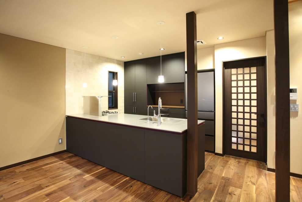 Foto på ett funkis linjärt kök, med släta luckor, svarta skåp, bänkskiva i rostfritt stål och en halv köksö