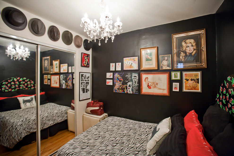 Photo of a small eclectic guest bedroom in New York with black walls, medium hardwood floors, no fireplace and brown floor.