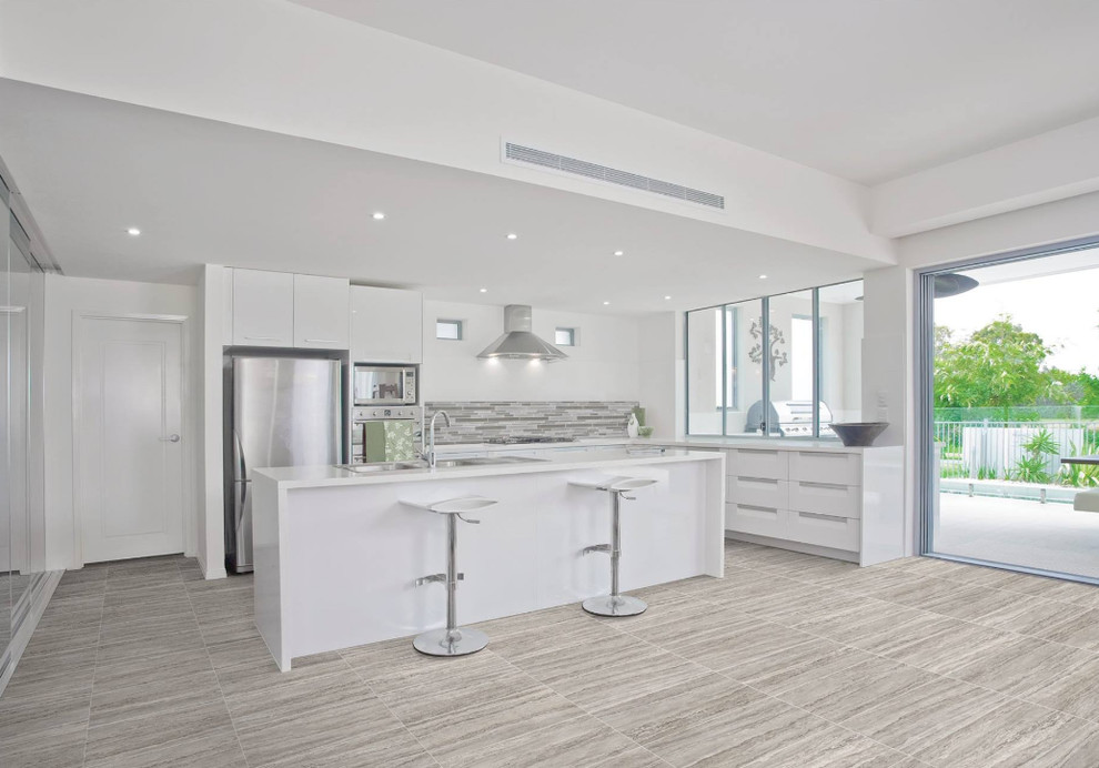 Example of a mid-sized minimalist l-shaped ceramic tile eat-in kitchen design in Indianapolis with a drop-in sink, flat-panel cabinets, white cabinets, solid surface countertops, gray backsplash, matchstick tile backsplash, stainless steel appliances and an island