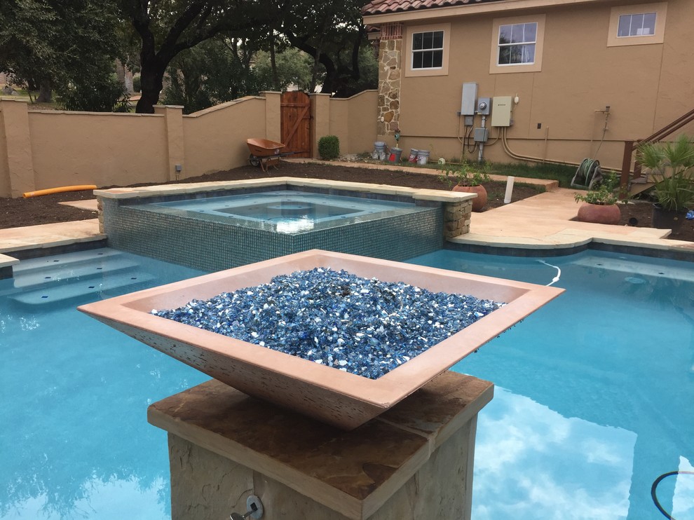 Example of a large mountain style backyard custom-shaped infinity hot tub design in Austin with decking