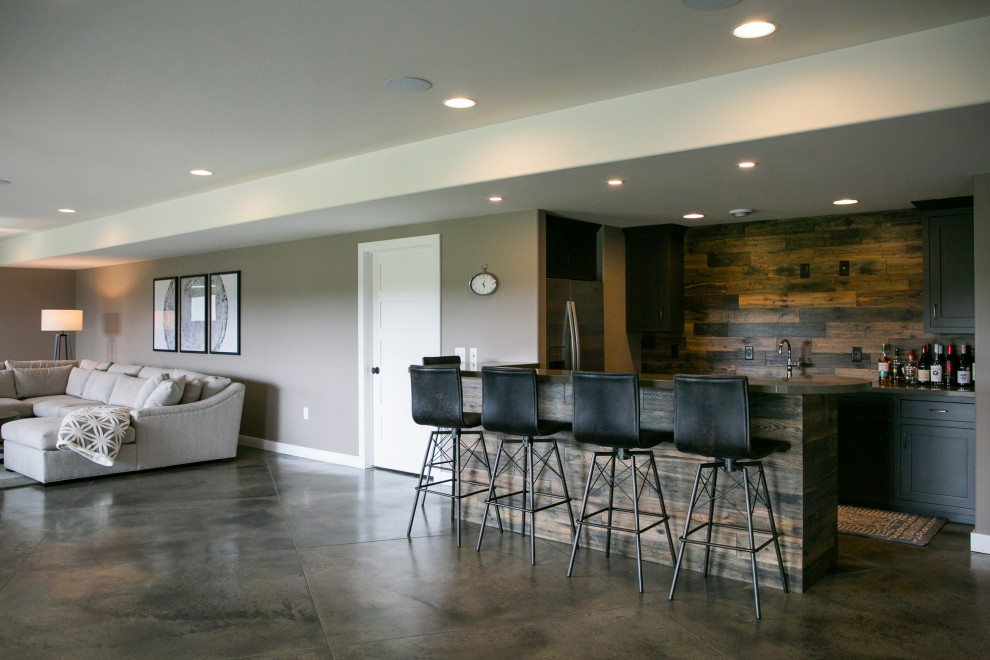Large trendy l-shaped concrete floor and gray floor wet bar photo in Chicago with shaker cabinets, gray cabinets, solid surface countertops, brown backsplash, wood backsplash and gray countertops