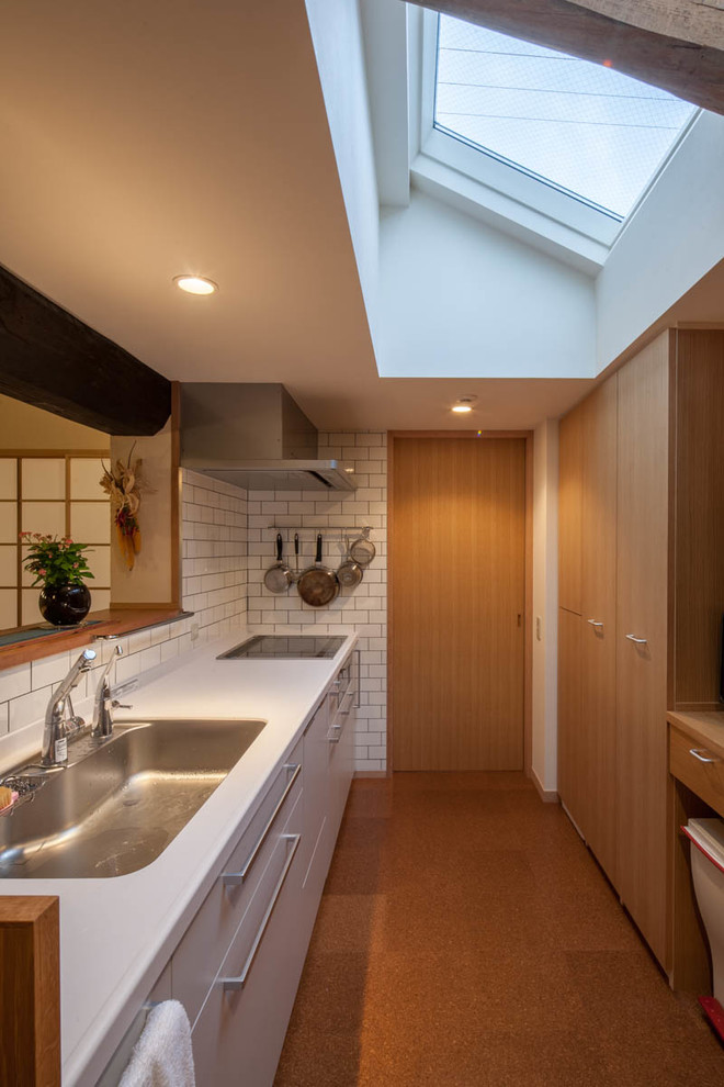 This is an example of a contemporary galley kitchen in Kyoto with an undermount sink, flat-panel cabinets, medium wood cabinets, white splashback, stainless steel appliances and no island.
