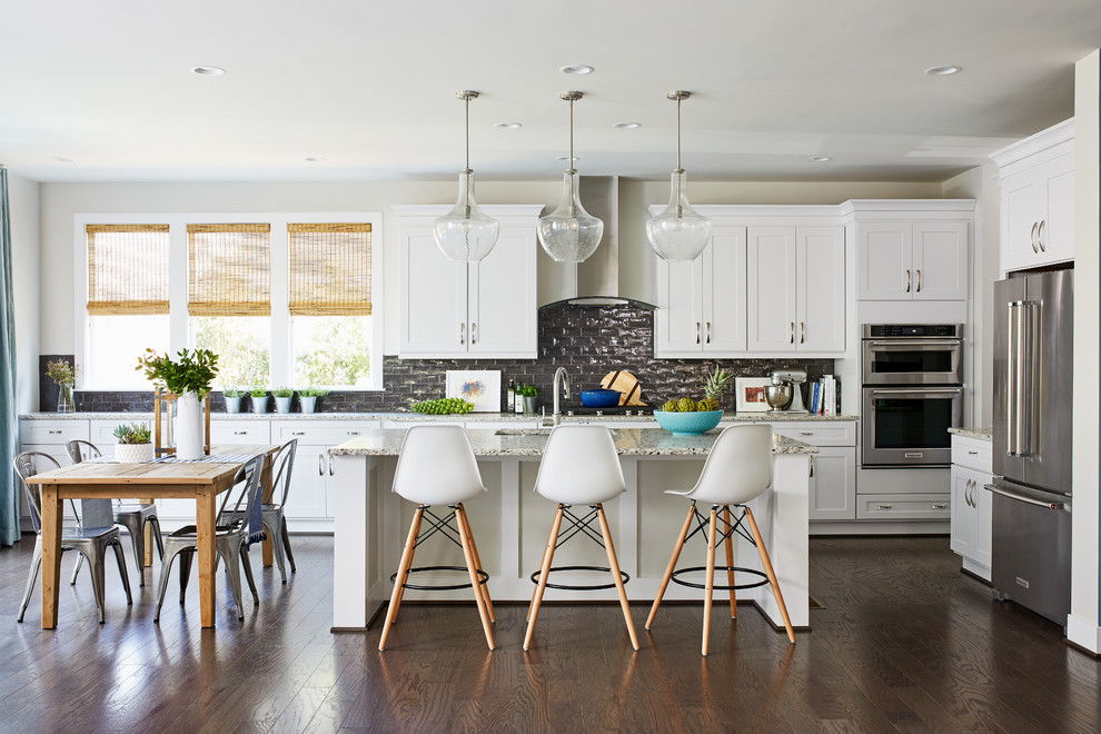 Inspiration for a mid-sized transitional l-shaped eat-in kitchen in Boston with an undermount sink, shaker cabinets, white cabinets, grey splashback, subway tile splashback, stainless steel appliances, dark hardwood floors, with island, brown floor and beige benchtop.