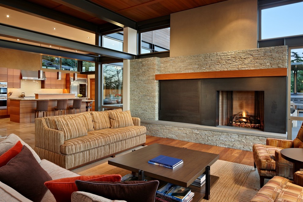 Contemporary open concept living room in Seattle with beige walls, a standard fireplace and a metal fireplace surround.