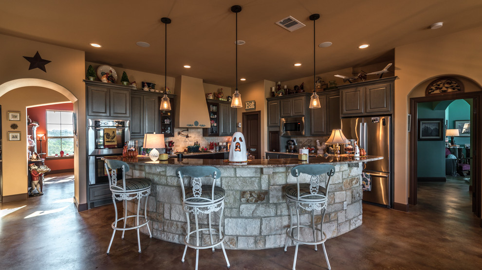 Eat-in kitchen - large rustic l-shaped concrete floor eat-in kitchen idea in Austin with a farmhouse sink, shaker cabinets, gray cabinets, granite countertops, beige backsplash, subway tile backsplash, stainless steel appliances and an island