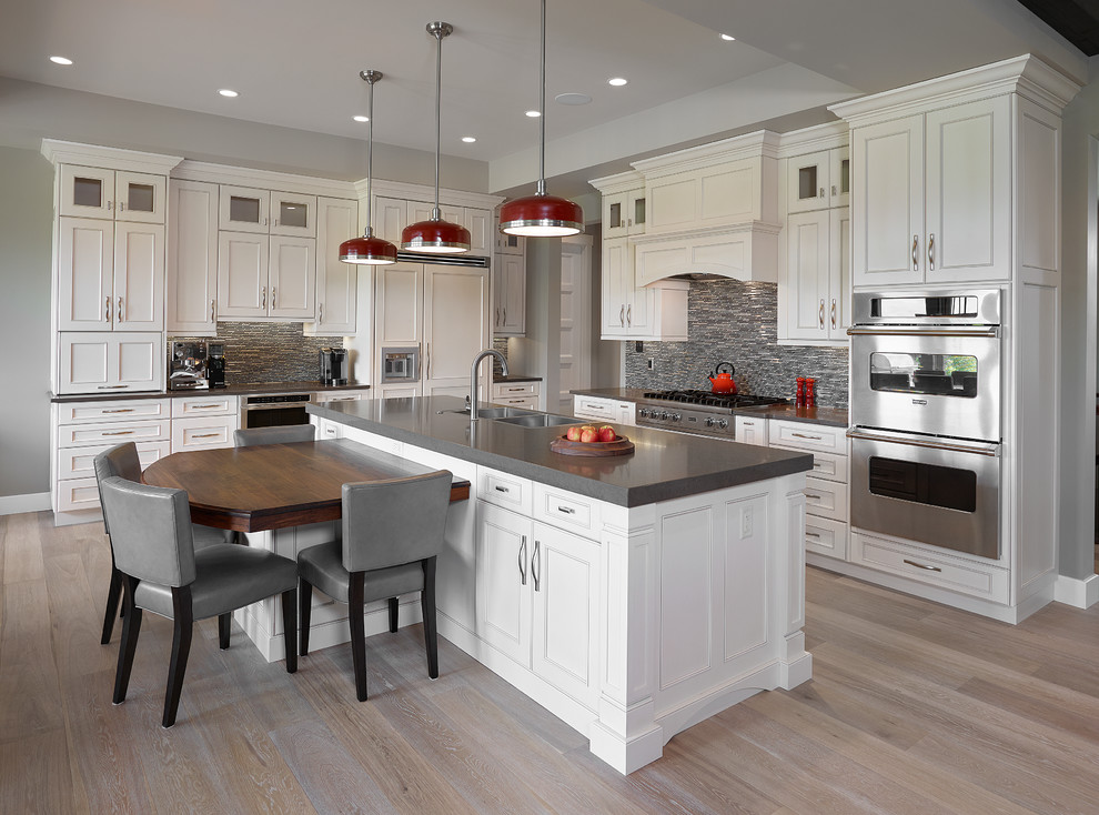 Large transitional l-shaped light wood floor and white floor eat-in kitchen photo in Edmonton with a farmhouse sink, recessed-panel cabinets, white cabinets, quartz countertops, gray backsplash, matchstick tile backsplash, stainless steel appliances and an island