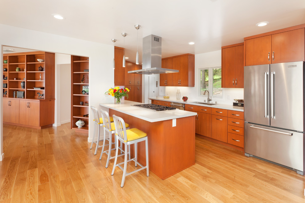 Photo of a contemporary galley open plan kitchen in San Francisco with an undermount sink, flat-panel cabinets, medium wood cabinets, quartzite benchtops, white splashback, subway tile splashback, stainless steel appliances, light hardwood floors, with island, beige floor and white benchtop.